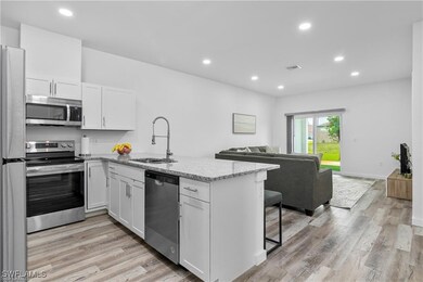 Kitchen with light hardwood / wood-style floors, sink, white cabinetry, kitchen peninsula, and stainless steel appliances