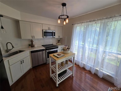 Kitchen with stainless steel appliances, backsplash, dark wood-style floors, and light countertops