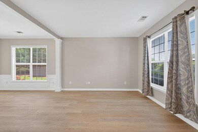 Empty room featuring light wood finished floors, wainscoting, and decorative columns