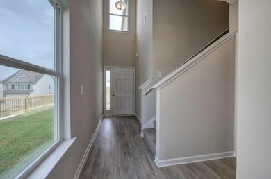 Entrance foyer featuring wood finished floors, stairway, a towering ceiling, and baseboards