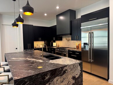 Kitchen with dark cabinetry, high end appliances,