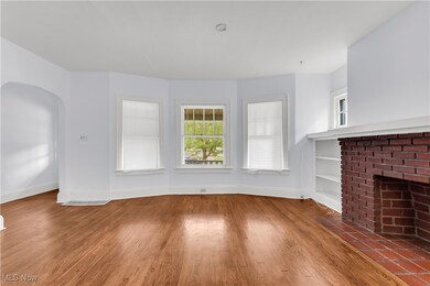 Unfurnished living room with hardwood / wood-style floors, a brick fireplace, and built in shelves