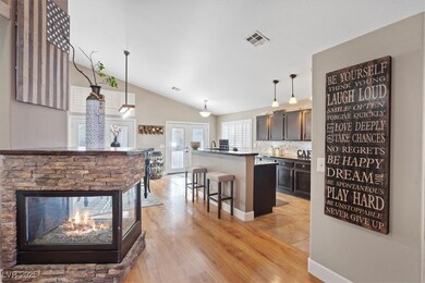 Kitchen featuring vaulted ceiling, a breakfast bar area, hanging light fixtures, light wood finished floors, and dark brown cabinets