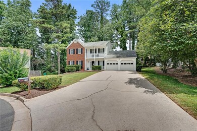 View of front facade with a chimney, concrete driveway, a front yard, an attached garage, and brick siding