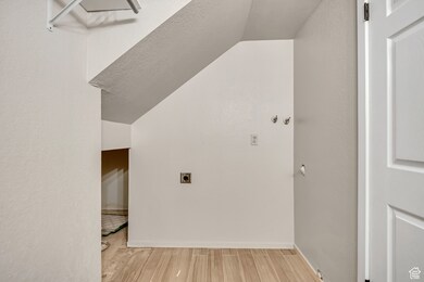 Additional living space with light wood-style floors and a textured ceiling