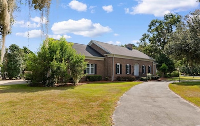 View of front facade with a front lawn, brick siding, driveway, and a chimney