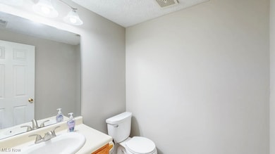 Half bathroom featuring vanity and a textured ceiling. Located off the entry foyer.