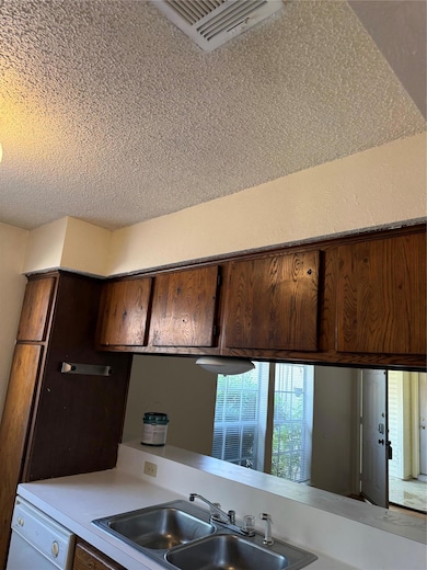 Kitchen featuring a textured ceiling, a sink, dis