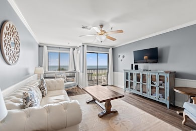Living room with crown molding, a ceiling fan, wood finished floors, and wainscoting