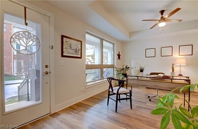Home office with ceiling fan, a tray ceiling, and light wood-type flooring