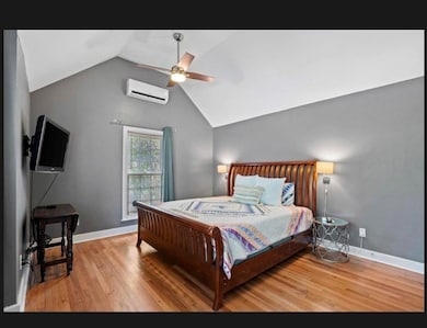 Bedroom with a wall unit AC, wood finished floors