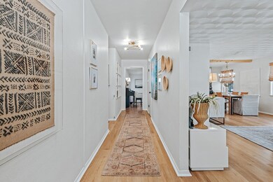 Hallway with light wood-style floors and a chandelier