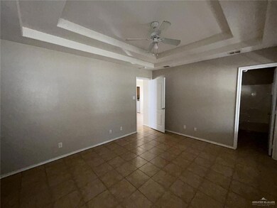 Tiled empty room featuring ceiling fan and a tray ceiling