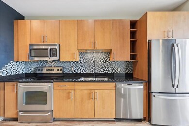Kitchen featuring stainless steel appliances, open shelves, dark stone counters, a sink, and decorative backsplash