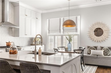 Kitchen featuring wall chimney range hood, pendant