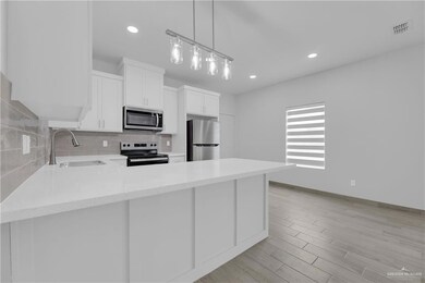 Kitchen with tasteful backsplash, white cabinets, sink, appliances with stainless steel finishes, and light hardwood / wood-style flooring