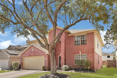 This charming two-story brick home features a two-car garage and a well-maintained front yard with mature trees.