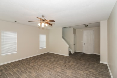 Unfurnished living room featuring dark wood-style floors, healthy amount of natural light, stairway, and a ceiling fan