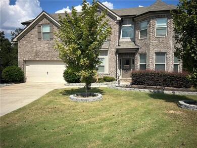 Traditional home with brick siding, a front lawn, concrete driveway, an attached garage, and roof with shingles