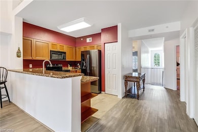 Kitchen with black appliances, dark stone countertops, light wood finished floors, a peninsula, and open shelves