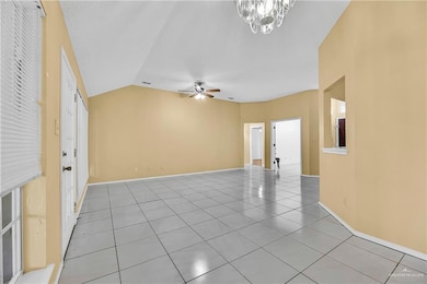 Unfurnished living room featuring light tile patterned flooring, lofted ceiling, ceiling fan, and a chandelier