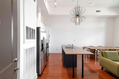 Kitchen featuring stainless steel fridge with ice dispenser, a sink, wood finished floors, a center island with sink, and a breakfast bar