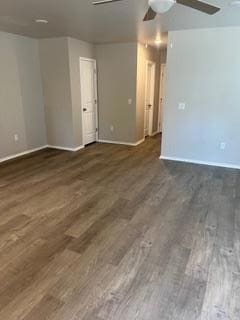 Empty room with a ceiling fan and dark wood-style flooring