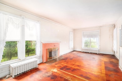 Unfurnished living room with hardwood / wood-style floors, a fireplace, radiator heating unit, and ornamental molding