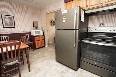 Kitchen featuring appliances with stainless steel finishes, ventilation hood, and wallpapered walls
