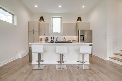 Kitchen with stainless steel appliances, decorative backsplash, a breakfast bar, decorative light fixtures, and large island