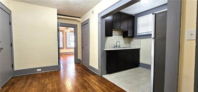 Kitchen with a sink, light countertops, hardwood / wood-style floors, backsplash, and dark cabinets