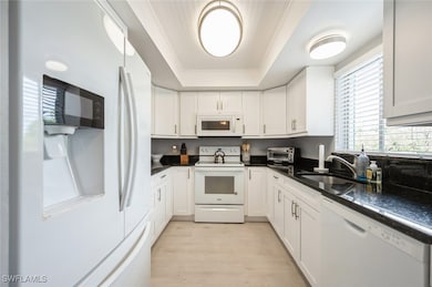 Kitchen featuring white appliances, a raised ceili