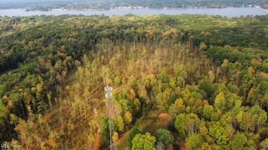 Aerial view of property and surrounding area featuring a nearby body of water and a heavily wooded area
