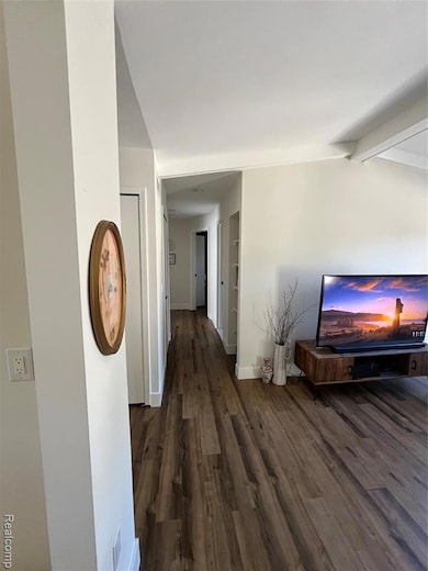 Corridor with dark wood-style floors and beamed ceiling