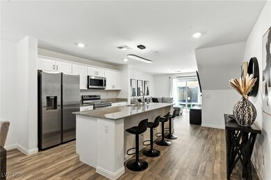 Kitchen featuring appliances with stainless steel finishes, an island with sink, white cabinetry, dark wood finished floors, and a kitchen breakfast bar