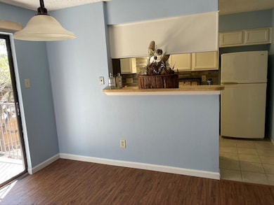 Kitchen with freestanding refrigerator, wood finished floors, pendant lighting, and backsplash