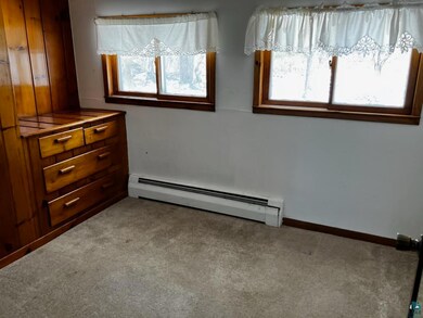 Bedroom with a baseboard heating unit and carpet