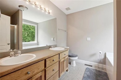 Full bathroom with a garden tub, double vanity, tile patterned floors, and an enclosed shower