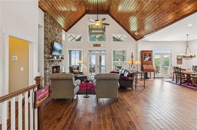Living area featuring a stone fireplace, dark wood-type flooring, french doors, a high ceiling, and ceiling fan