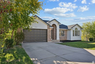 Single story home featuring stucco siding, concrete driveway, brick siding, an attached garage, and a front lawn