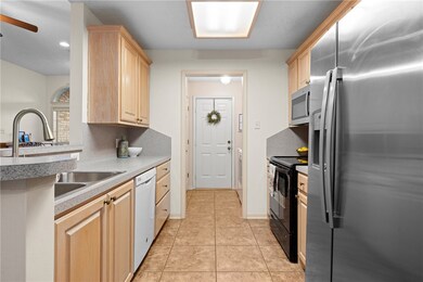 Kitchen featuring appliances with stainless steel finishes, light brown cabinetry, tile floors, and countertops