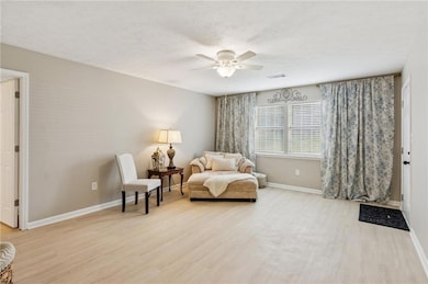 Living area featuring light wood finished floors, ceiling fan, and a textured ceiling