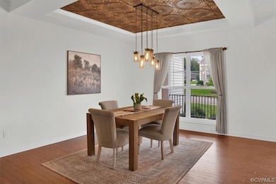 Wood floored dining room with a tray ceiling and a
