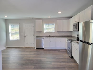 Kitchen featuring white cabinetry, stainless steel appliances, sink, and a wealth of natural light