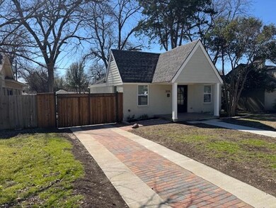 Bungalow-style home with a gate, brick siding, fen