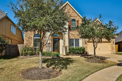Great curb appeal featuring mature landscaping and a two-story stone and brick entrance.