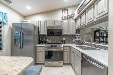 Kitchen with appliances with stainless steel finishes, light countertops, decorative backsplash, light tile patterned floors, and gray cabinets