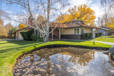 View of front of property featuring a front lawn, a garage, a chimney, and stucco siding