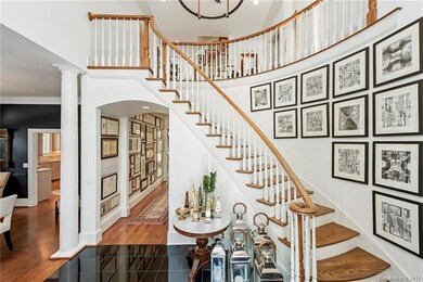 Grand foyer boasts curved staircase and a large la