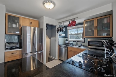 Kitchen featuring glass insert cabinets, backsplash, appliances with stainless steel finishes, and brown cabinets